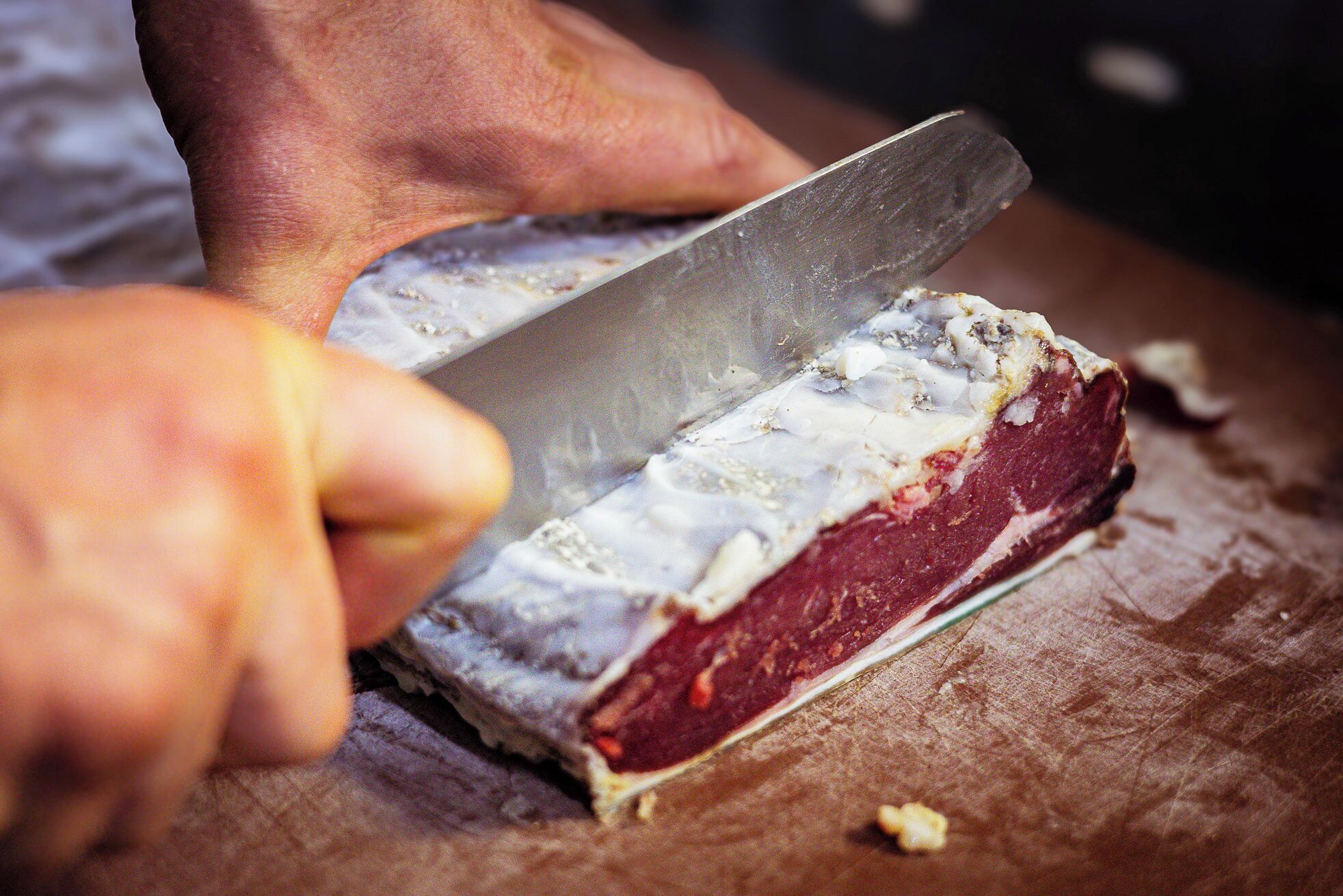 Une personne qui découpe une grande pièce de viande sur une planche à découper en bois.