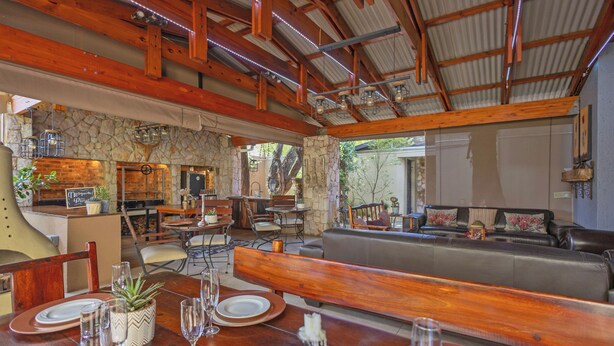 Un vaste espace extérieur aménagé pour les repas, avec des tables et des bancs en bois, des murs en pierre et une cheminée en pierre.