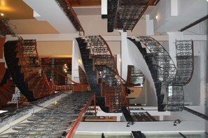 A modern interior with multiple staircases featuring ornate metal railings and glass railings. - Casona Plaza Hotel Centro (Puno)
