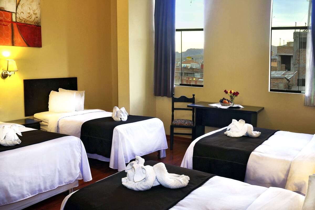 A hotel room with three beds, a desk, and a chair.