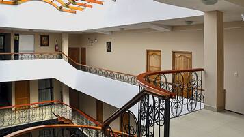 A multi-level interior with a curved staircase, metal railings, and wooden doors.