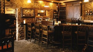 A bar area with wooden chairs, a stone wall, and a bar counter with bottles. - Racket Hall Country House (Roscrea)