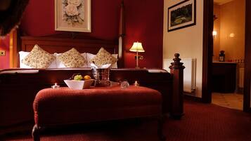 Une chambre d’hôtel avec un grand lit, une table de chevet avec une lampe, un sol recouvert d’une moquette rouge et un tableau encadré au mur.