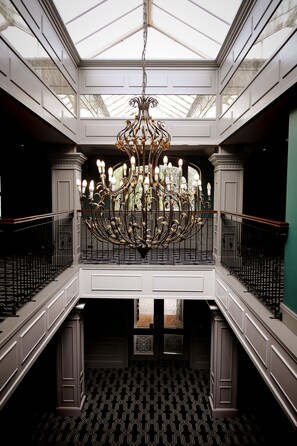 A grand chandelier in a spacious atrium with a high ceiling and patterned floor.