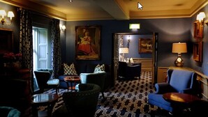 A room with a patterned floor, a blue armchair, a small table, and a chair with a patterned cushion. - Racket Hall Country House (Roscrea)