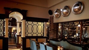 A dining area with a brick wall, metal decorative panels, and a large mirror. - Racket Hall Country House (Roscrea)