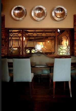 A restaurant interior with a brick wall, a wooden partition with a geometric pattern, and three circular wall decorations.