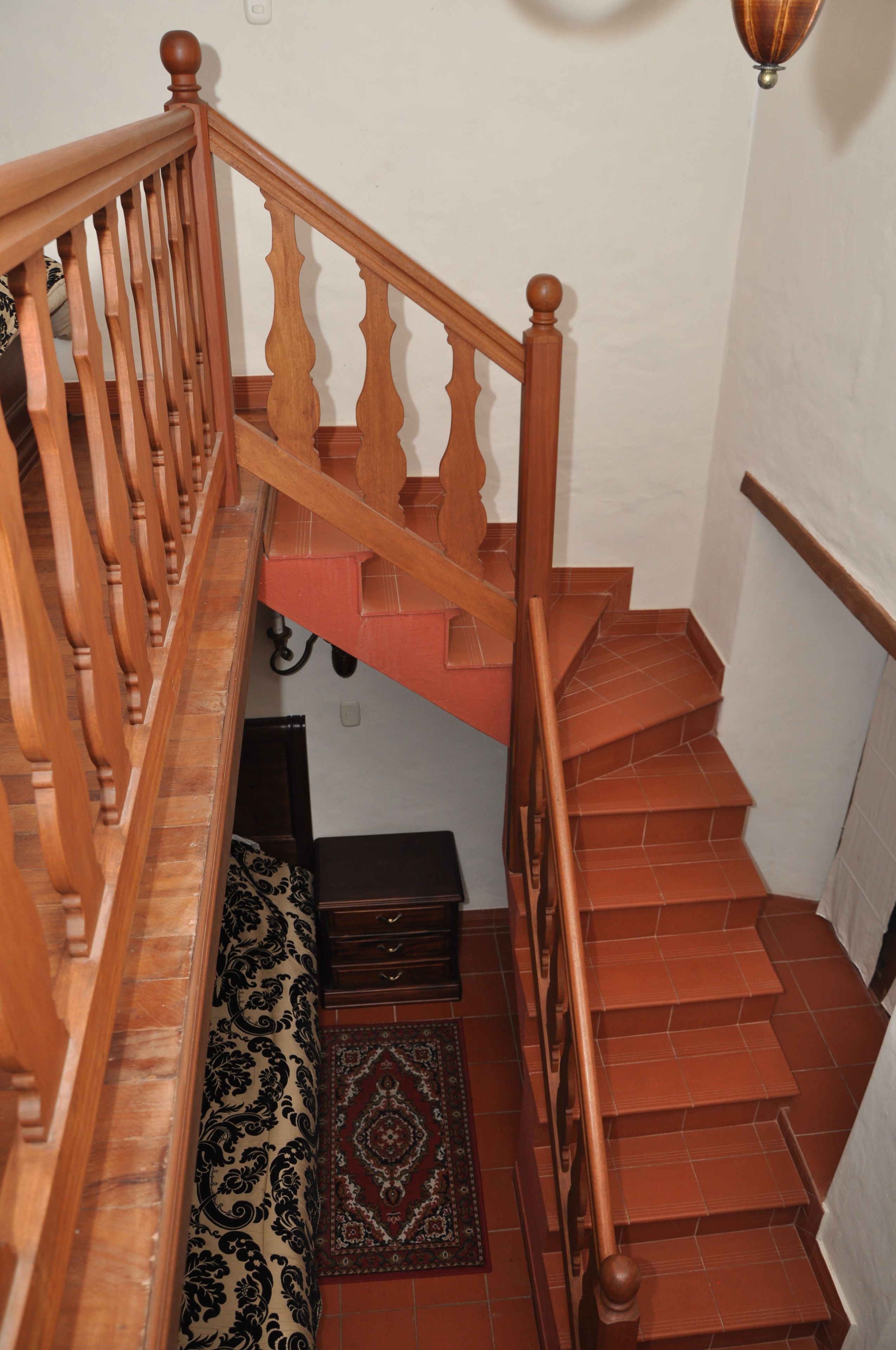 Uma escada de madeira com corrimão e um tapete estampado nos degraus.