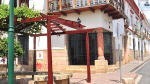 A traditional two-story building with a balcony, a street lamp, and a bench.