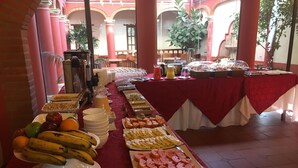 A buffet table with various food items and a red tablecloth.