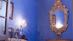 A bedroom with a large bed, a chandelier, a mirror, and a window with curtains.