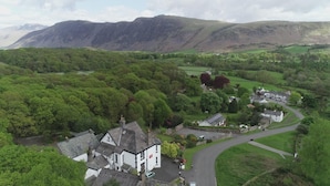 A rural village with traditional stone houses, a winding road, and a backdrop of mountains. - Low Wood Hall Hotel (Seascale)