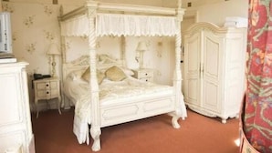 A four-poster bed with a canopy, a nightstand, a wardrobe, and a mirror. - Low Wood Hall Hotel (Seascale)