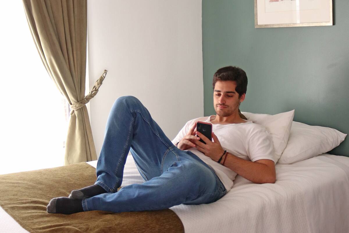 A person lying on a bed in a room with a green wall and a framed picture.