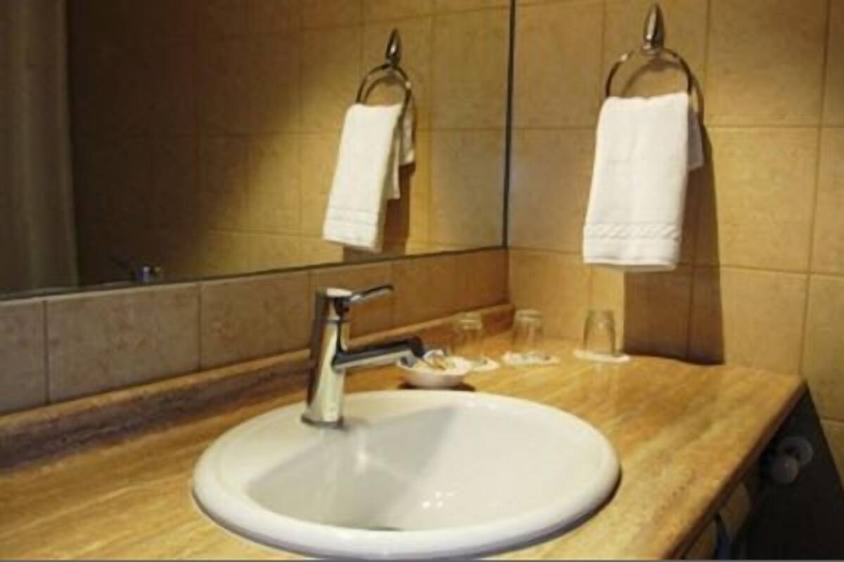 A bathroom with a sink, mirror, and towel rack.