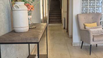 A hallway with a long table, a chair, and a staircase in the background.