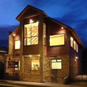 Un bâtiment à deux étages, avec une façade en pierre et en bois, de nombreuses fenêtres et une enseigne bien visible.