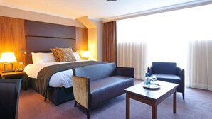 Una habitación de hotel con una cama, dos sillas, una mesa y una mesita de noche.