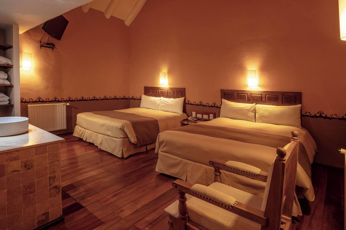 Ein Hotelzimmer mit zwei Betten, Holzboden, Nachttisch und Heizkörper.