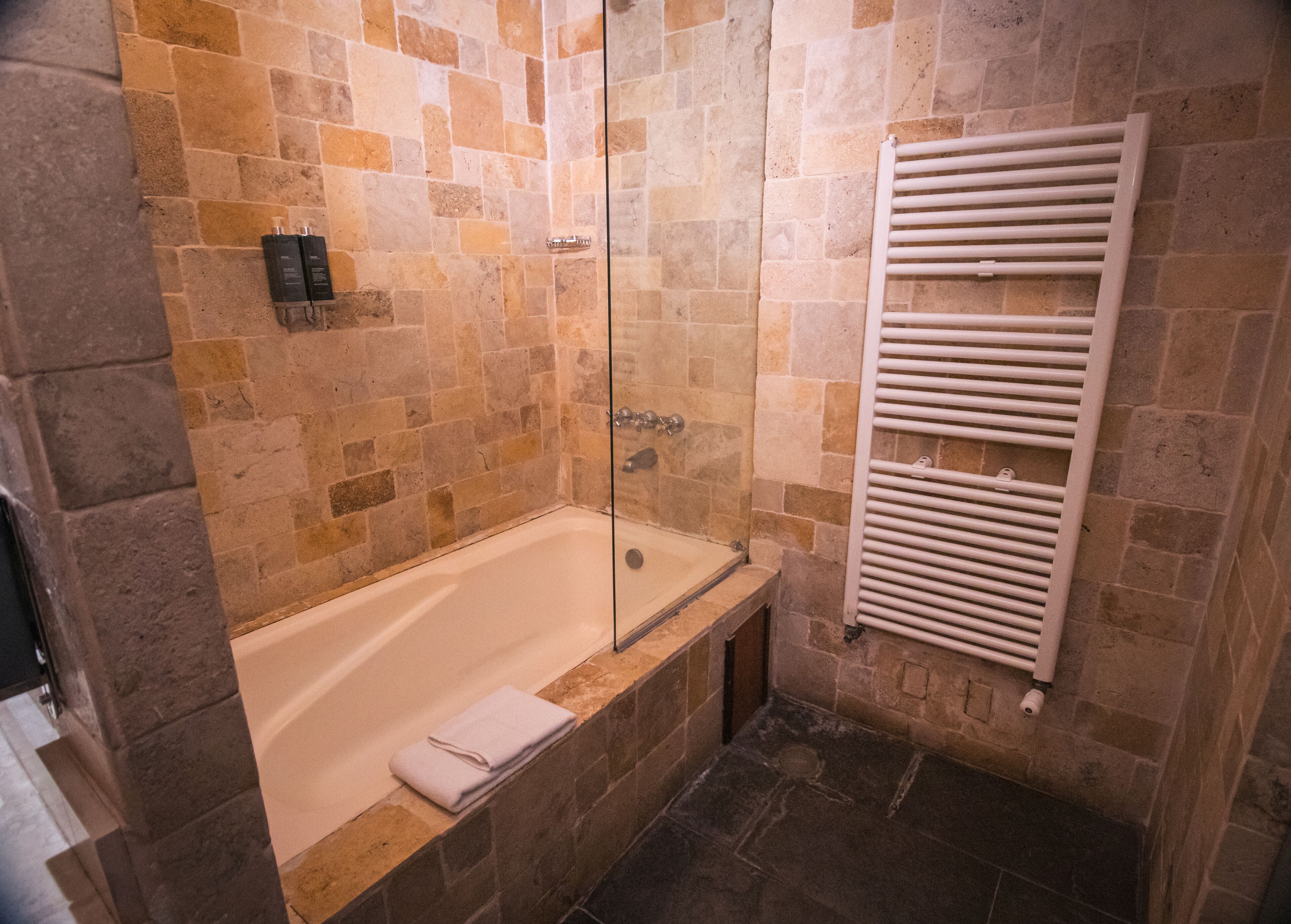 A bathroom with a bathtub, a glass shower enclosure, and a towel rack.