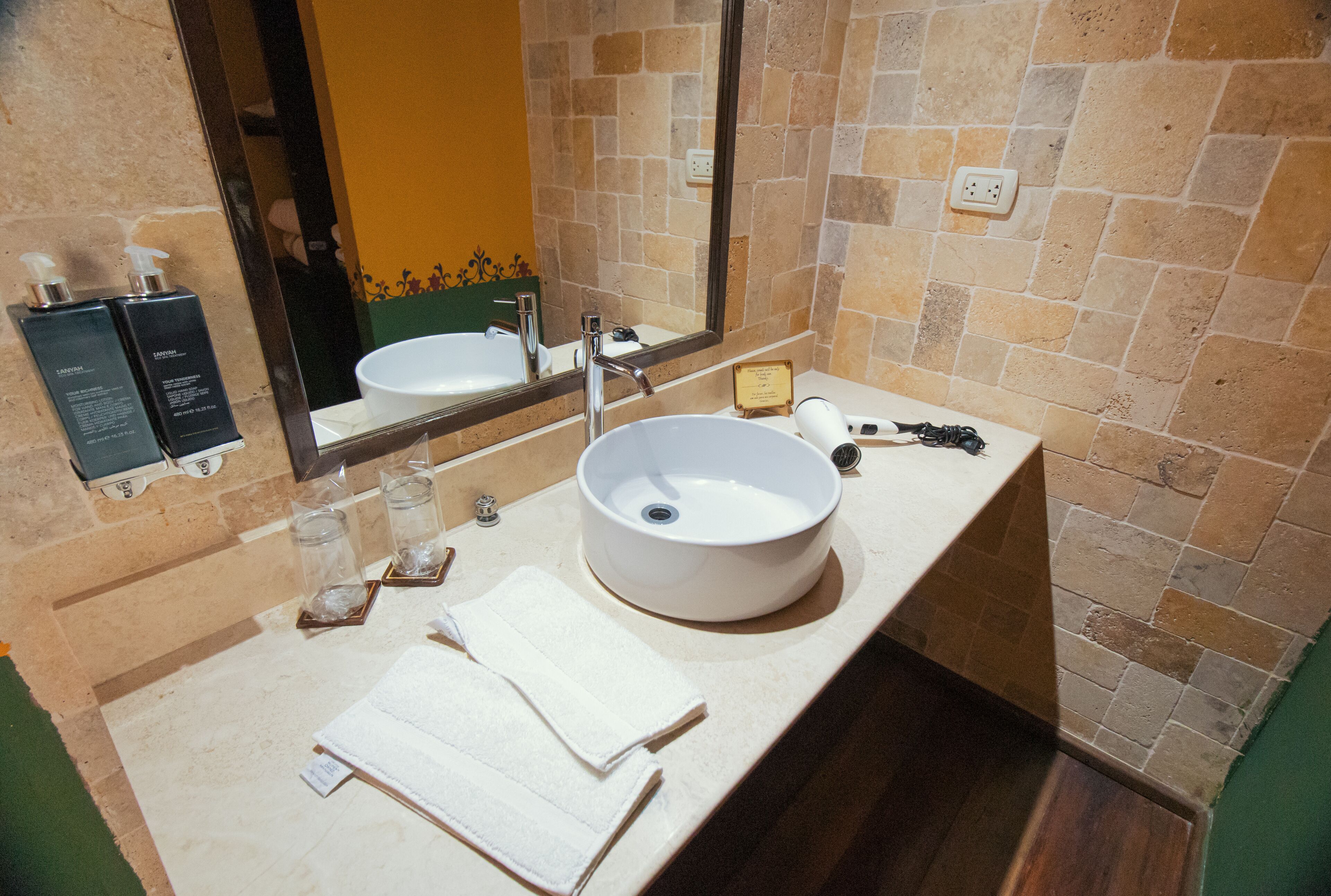 A bathroom with a white sink, a mirror, and toiletries on the counter.