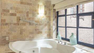 Un baño con bañera independiente, una toalla y ventana con vistas.