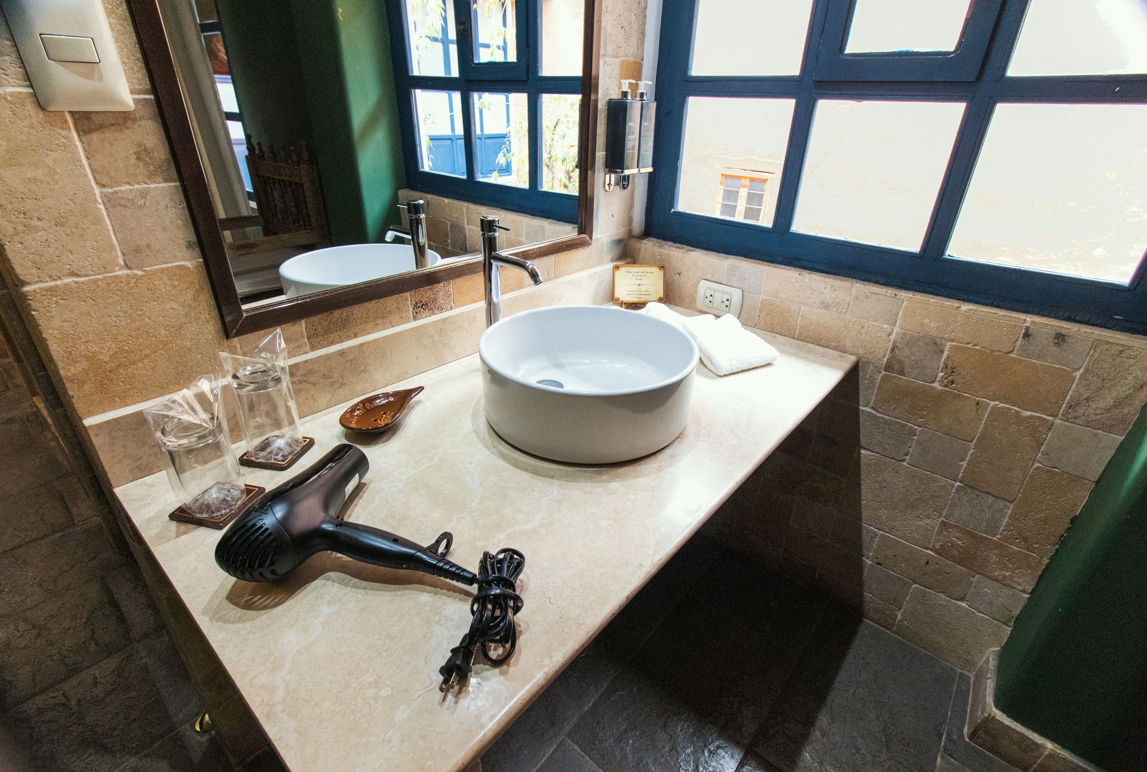 A bathroom with a sink, mirror, and a hairdryer on the counter.