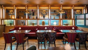 Un restaurante con cabinas de madera, asientos tapizados en rojo e iluminación colgante.