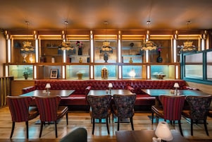 Un restaurante con cabinas de madera, asientos tapizados en rojo e iluminación colgante.