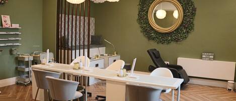 A salon with a long white desk, grey chairs, and a mirror on the wall.