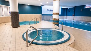 Una piscina interior con hidromasaje, suelo de baldosas y un cartel que dice 'TRANQUILL' al fondo.