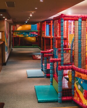 A play area with colorful netted structures and padded platforms.
