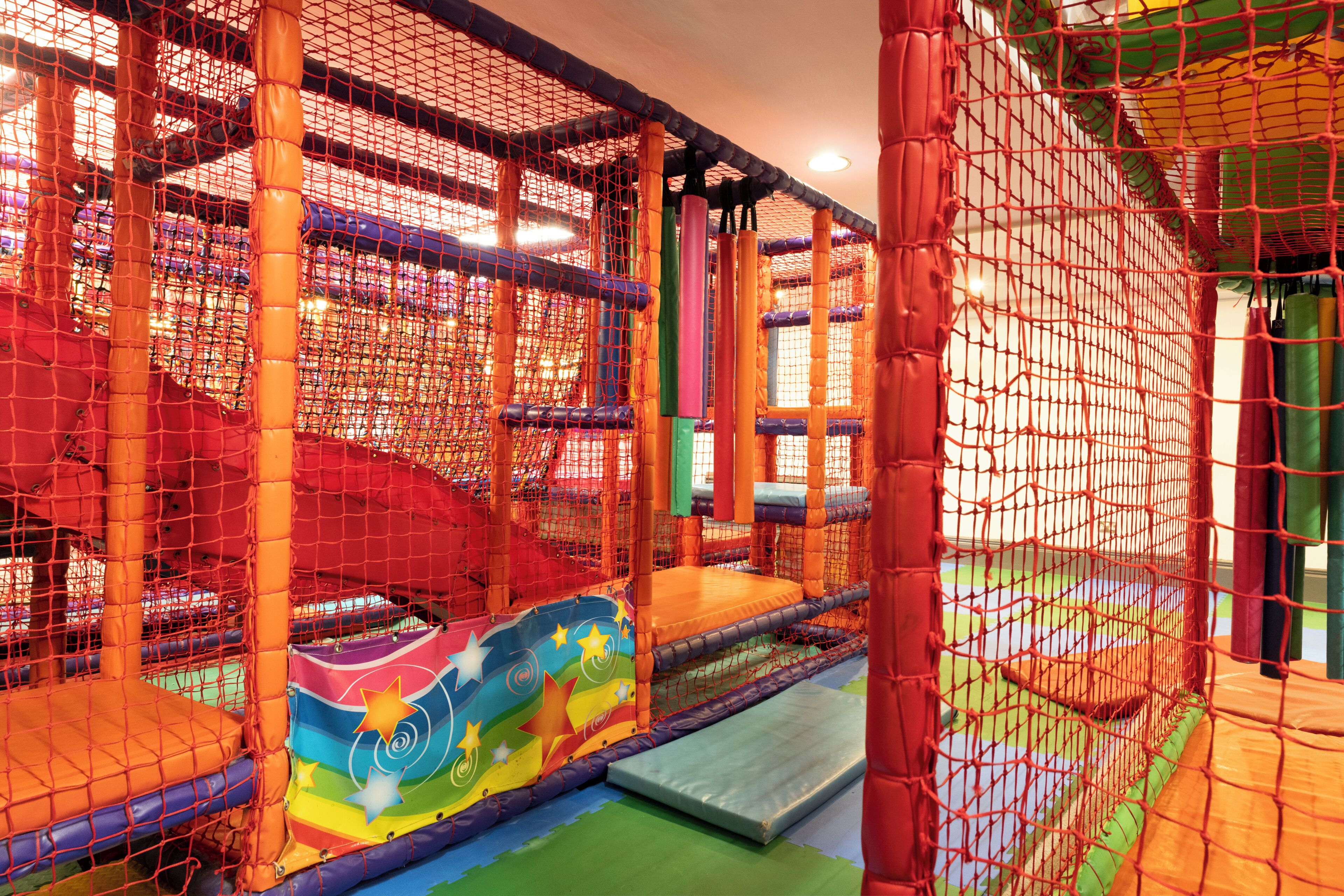 A play area with netted structures and padded surfaces.