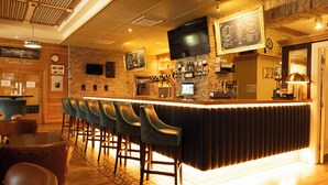 Un área de bar con techo de madera, taburetes, una barra con menú y un televisor montado en la pared.