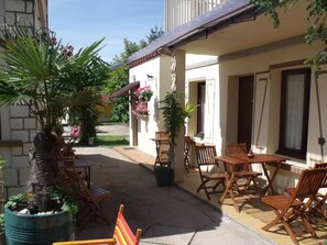 A courtyard with outdoor seating, a palm tree, and potted plants. - Le Clos Robinson (Martin-Eglise)