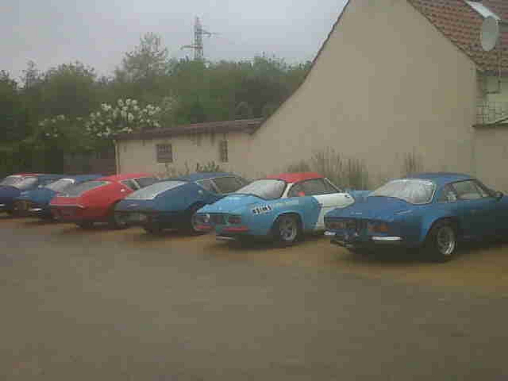 A row of parked cars in front of a building with a sloped roof.