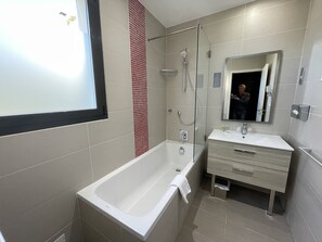 A modern bathroom with a bathtub, a shower, and a vanity with a mirror. - Hotel Baptistin (Le Lavandou)