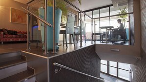 Een modern interieur met een trap, een bank en een eethoek met stoelen en een tafel.