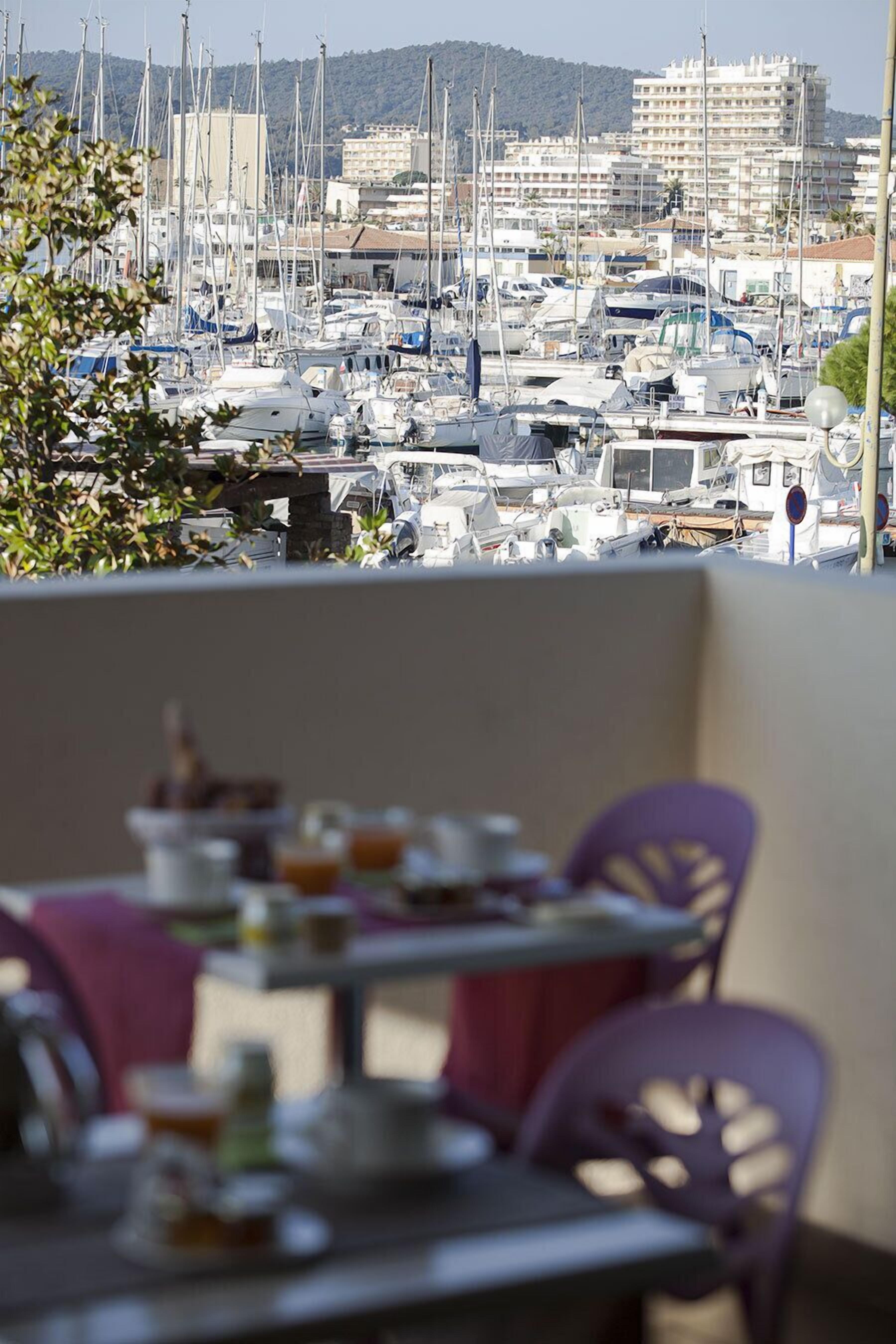 Ein Balkon mit Esstisch, der auf einen Yachthafen mit zahlreichen Booten blickt.