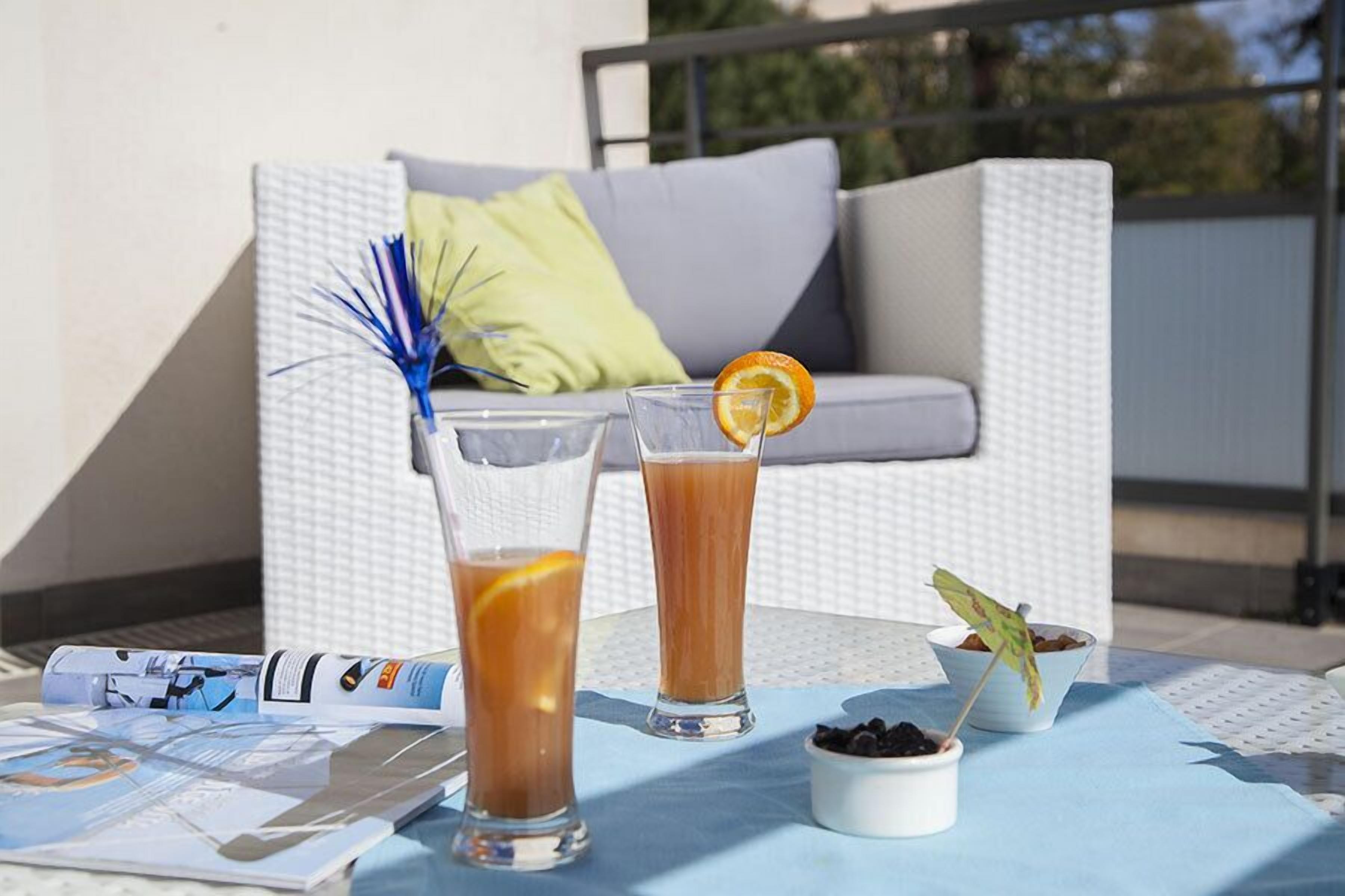 Twee drankjes op een tafel, met een tijdschrift, een schaal chocolade en een kleine plant.