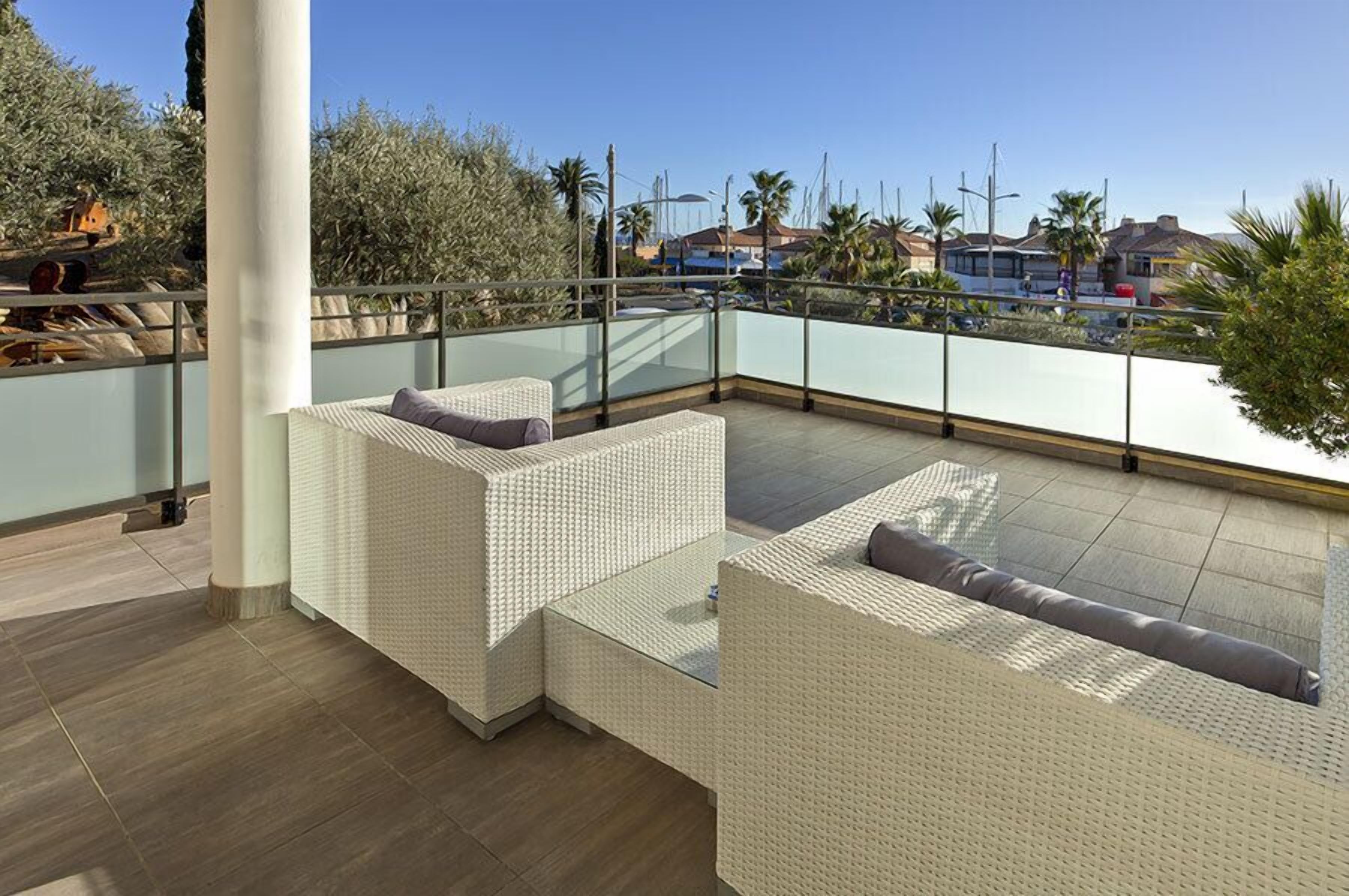 A rooftop terrace with wicker furniture and a view of the marina.