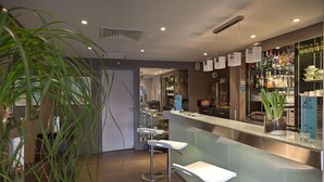 Een moderne bar met een toonbank, krukken en een divers aanbod aan flessen en glazen.