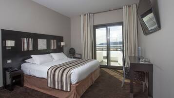 Une chambre d’hôtel avec un grand lit, un bureau, une chaise, un téléphone et une vue sur l’extérieur.