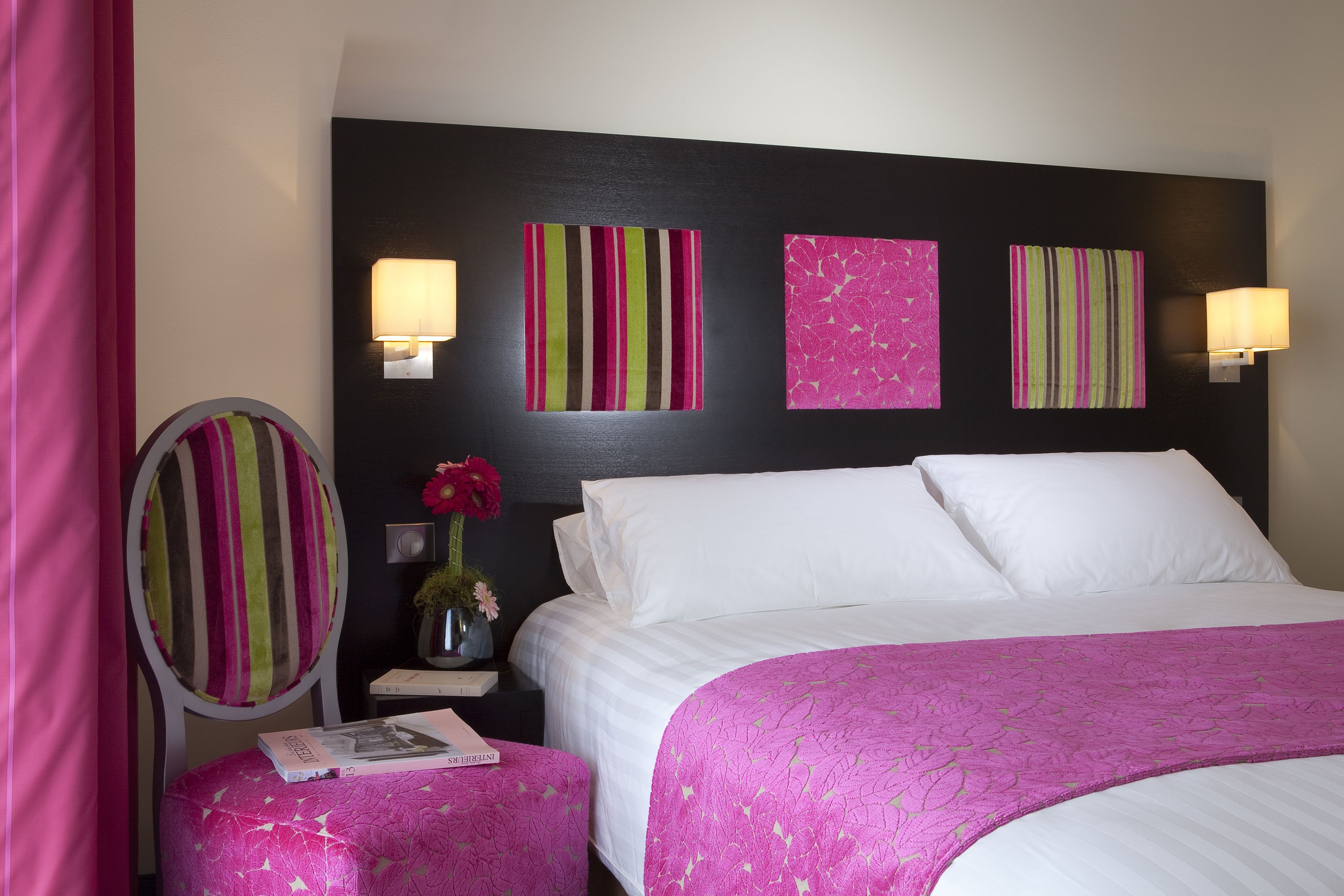Een hotelkamer met een bed, een nachtkastje met een lamp, een kaptafel met spiegel en kunst aan de muur.