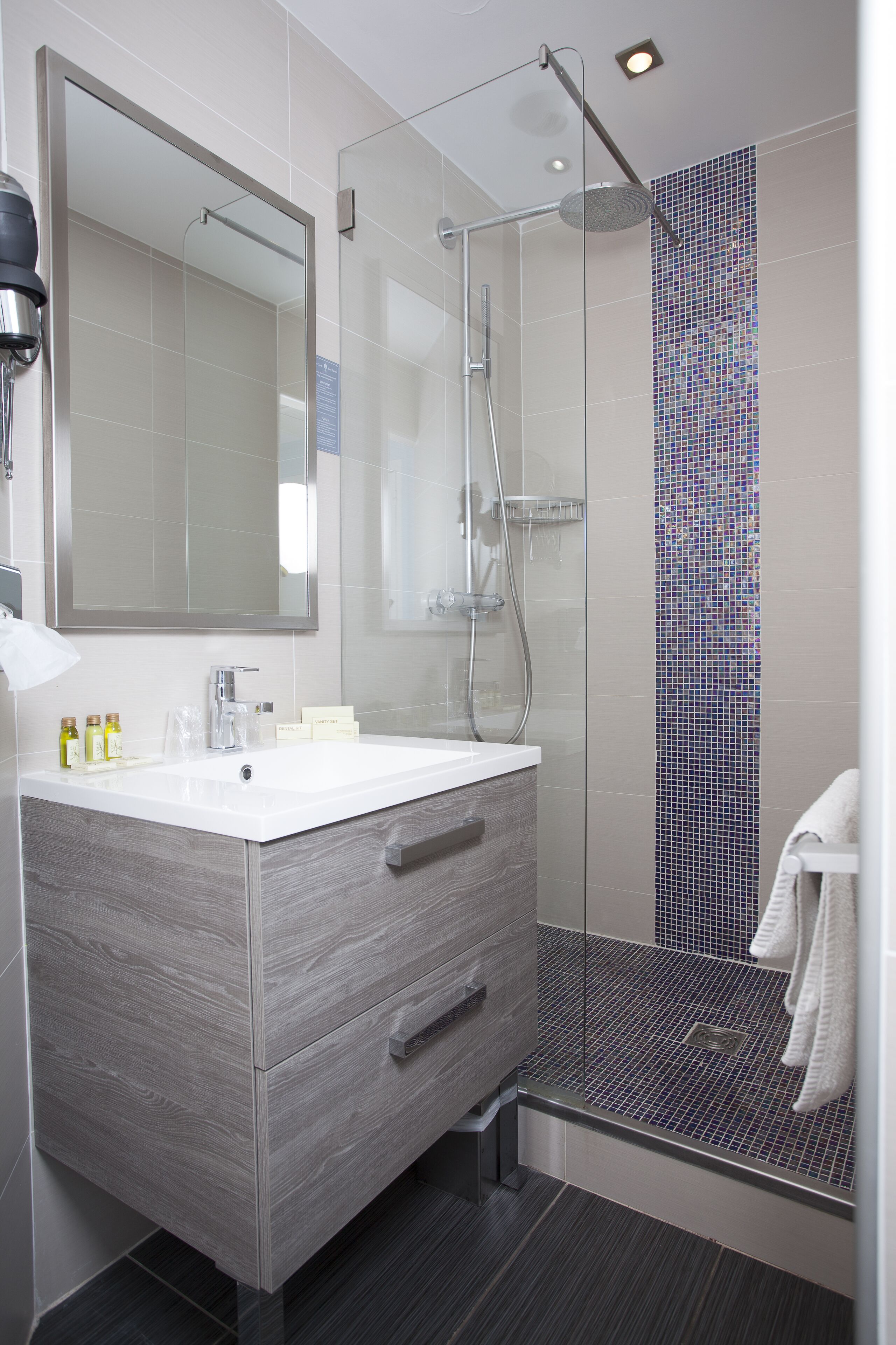 Un bagno moderno con doccia vetrata, un grande specchio e un mobile vanità con cassetti.