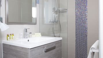 Un bagno moderno con doccia vetrata, un grande specchio e un mobile vanità con cassetti.