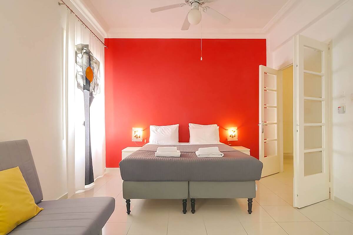 A bedroom with a bed, bedside tables, a ceiling fan, and a nightstand with a lamp.