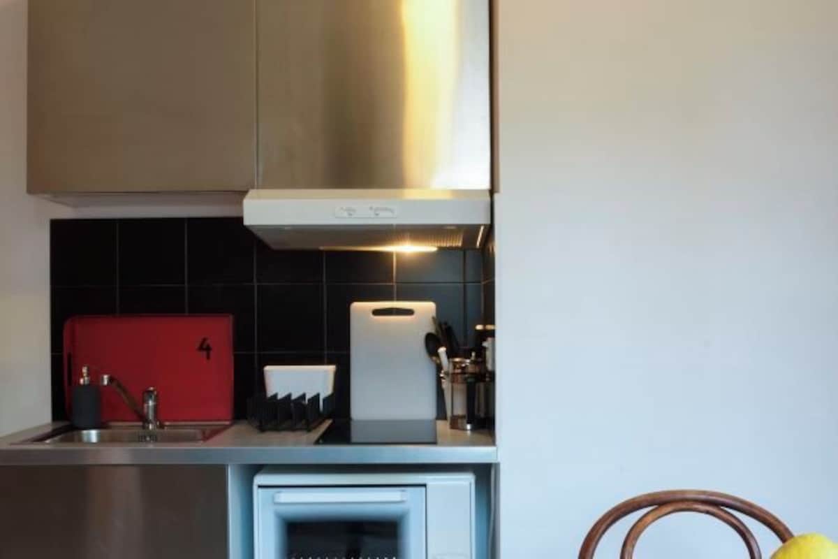 A kitchen with a stainless steel range hood, a red appliance, and a white oven.
