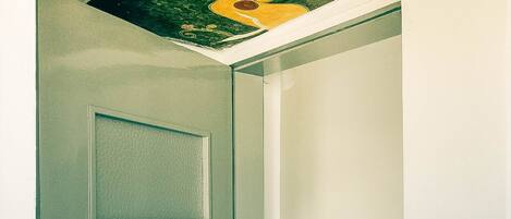 Un pasillo con una puerta, una lámpara de cristal y un techo con ilustraciones coloridas.