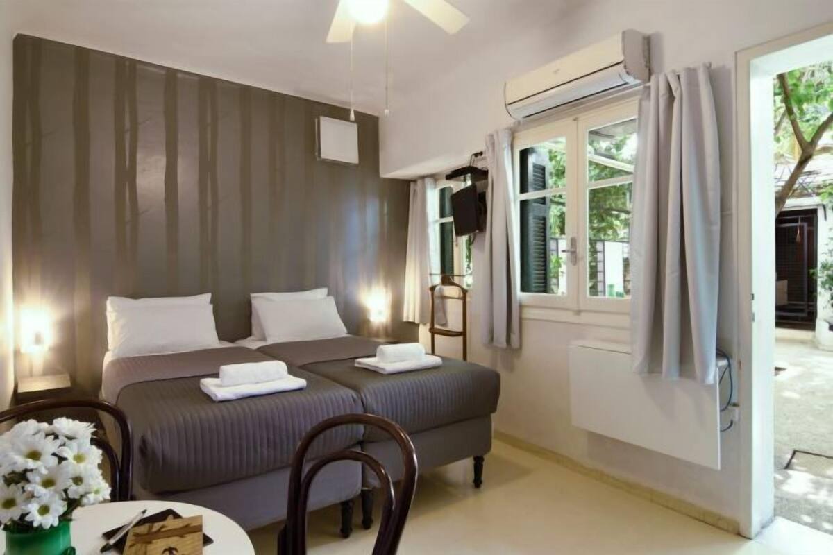 A bedroom with a bed, bedside table, chair, and a window with curtains.